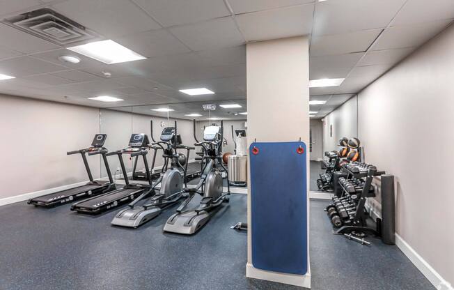 A gym with treadmills, exercise bikes, and weights at 7 Cameron Apartments, Massachusetts