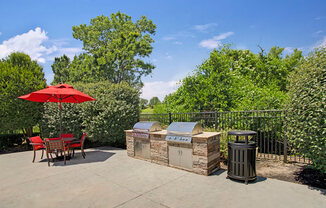 a patio with a barbecue grill and a table and chairs