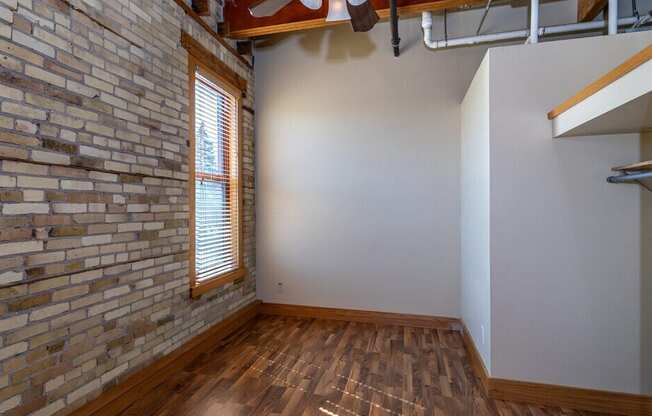 A room with a brick wall and wooden flooring.