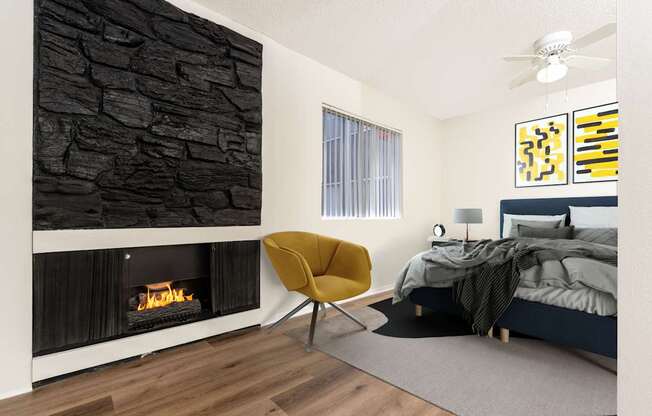 A modern bedroom with a stone wall and a yellow chair.