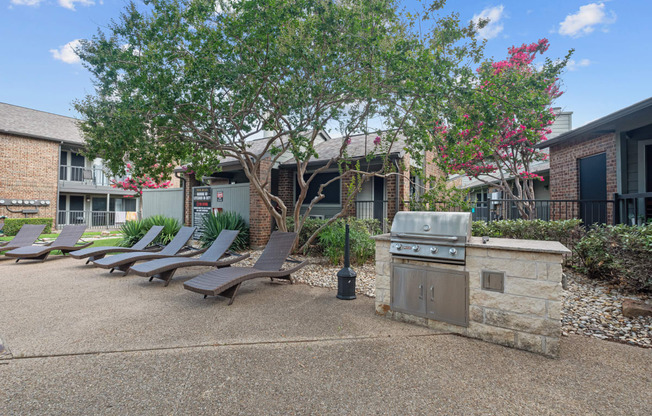 a barbecue and lounge chairs at the whispering winds apartments in pearland, tx