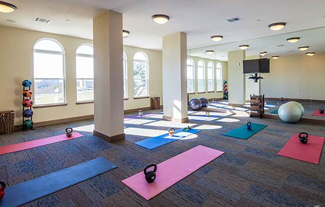 a yoga studio with yoga mats and dumbbells on the floor