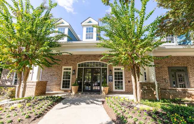 the front entrance of a brick building with trees and a sidewalk