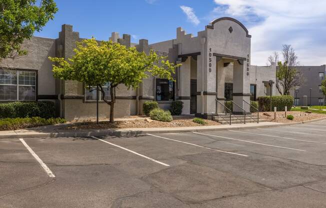 a building with a parking lot and a tree in front of it
