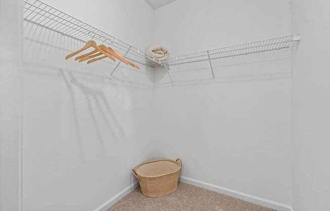 A white closet with a wire shelf and a basket on the floor.
