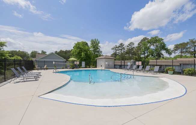 our apartments have an outdoor pool with chairs and trees