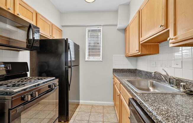 A kitchen with black appliances and wooden cabinets.