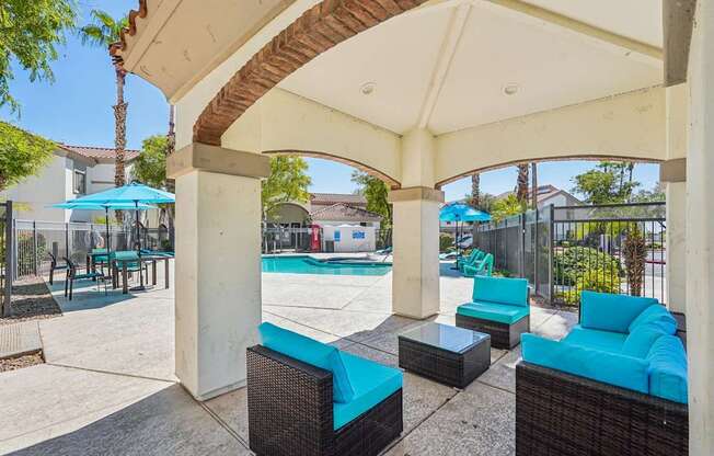 A patio with a pool and a blue umbrella.
