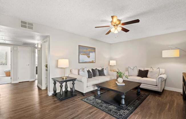 A living room with a white couch, a coffee table, and a ceiling fan.