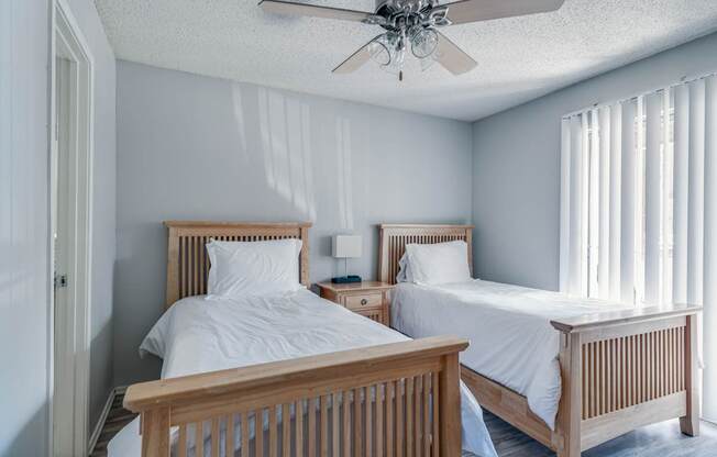 A bedroom with two beds and a ceiling fan.