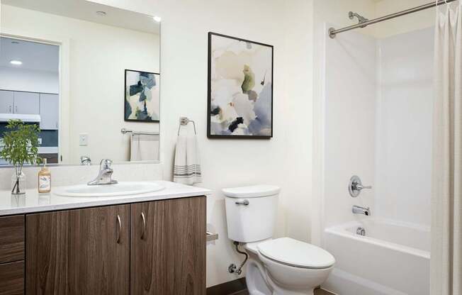 A white toilet sits in a bathroom next to a sink and a bathtub.
