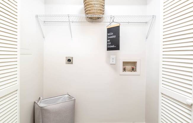 a white bathroom with a trash can and a rack on the wall