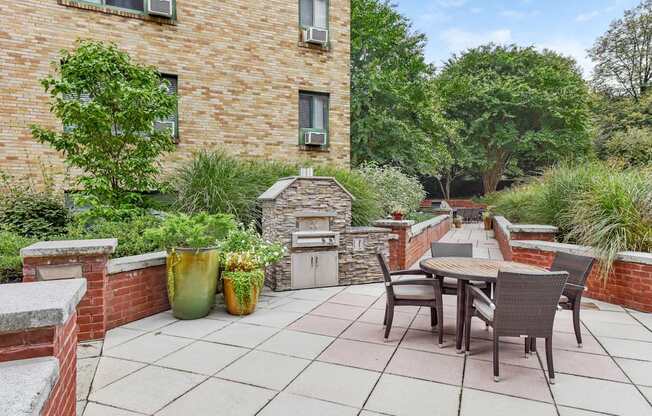 A patio with a table and chairs is surrounded by a brick wall and has a fireplace.