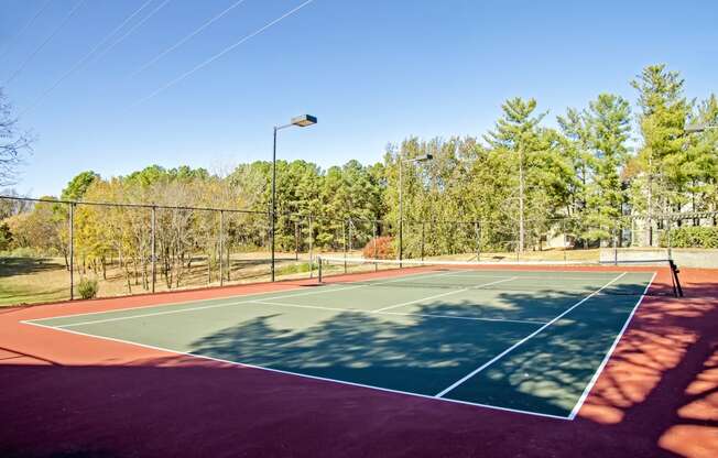 a tennis court with a fence and trees in the background