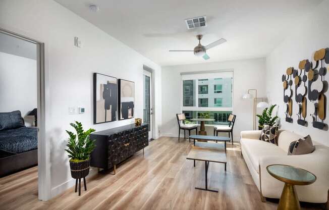 A living room with a black couch, a white couch, a coffee table, and a ceiling fan.