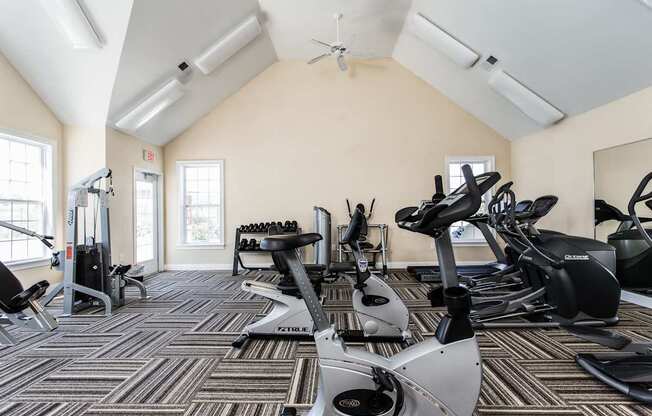 A gym with a variety of exercise equipment including treadmills, stationary bikes, and elliptical machines.