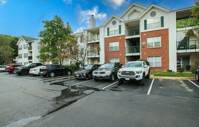 a parking lot with cars in front of an apartment building
