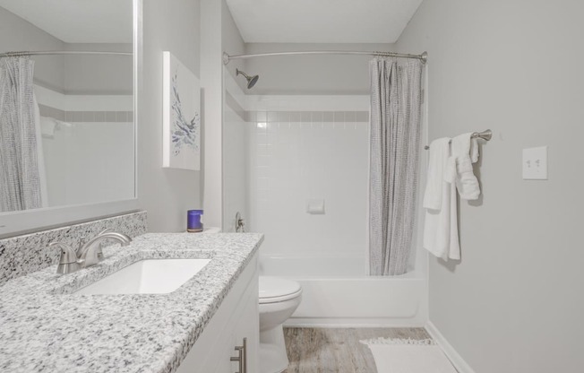 Bathroom with granite countertop and shower/tub combo with curved shower rod