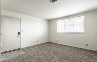 an empty room with carpet and a window and a door