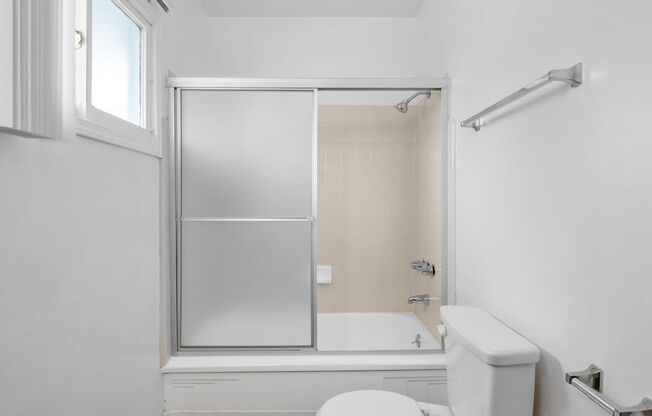 a white bathroom with a shower and a toilet