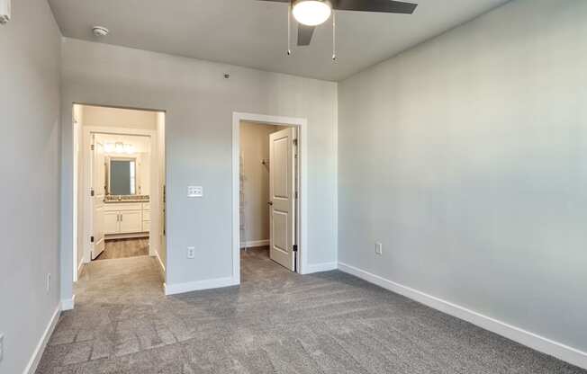 an empty living room with white walls and a ceiling fan at The Bella at Westchester, Midlothian, VA, 23113