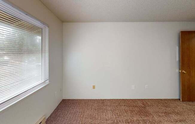 Second bedroom in a 2-bedroom unit at Heritage Grove Apartments Renton WA, with soft carpeting, large closet space, and a light-filled window.