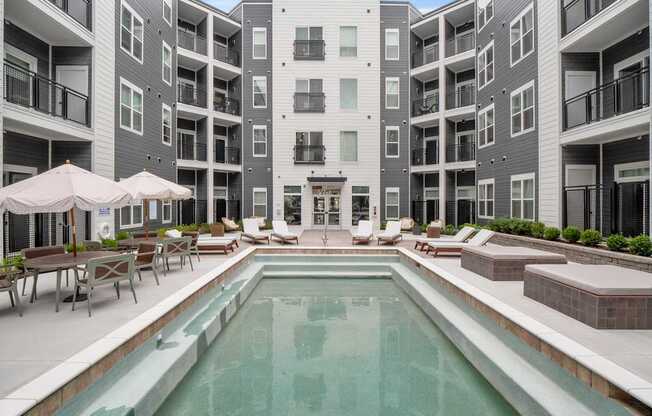 A large swimming pool in the middle of a courtyard surrounded by apartment buildings.