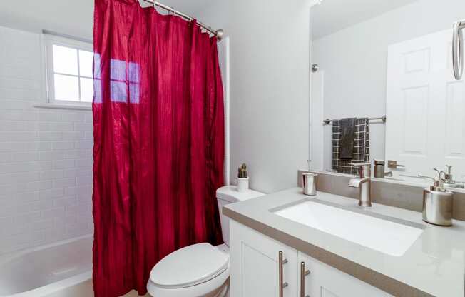 a bathroom with a red shower curtain and a toilet and sink