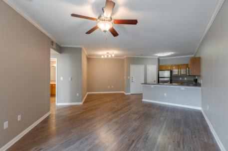 A spacious room with a ceiling fan and hardwood flooring.