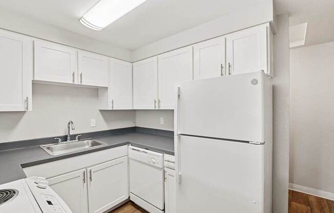 A white refrigerator is in a kitchen with white cabinets.