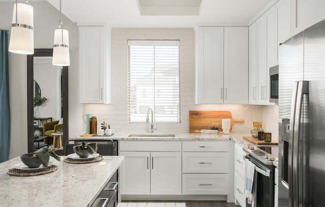 A kitchen with white cabinets and a marble countertop.