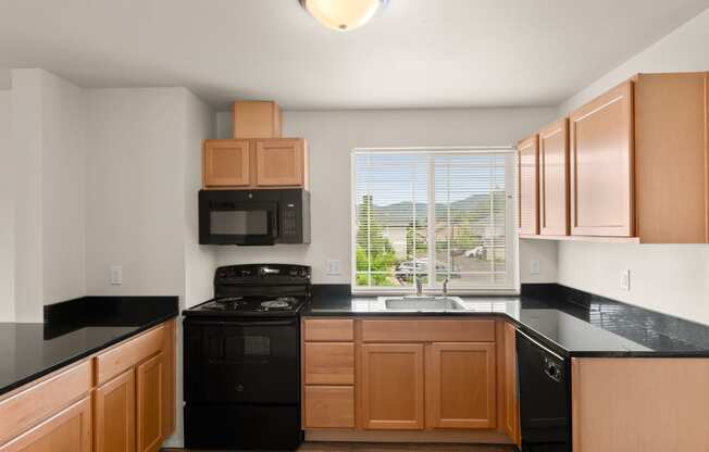 an empty kitchen with black counter tops and wooden cabinets