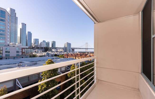A balcony overlooks a cityscape with a bridge in the distance.