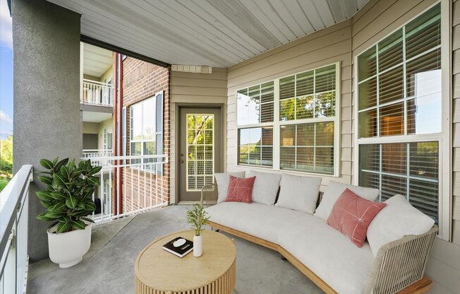 A white sofa with red pillows sits on a patio.