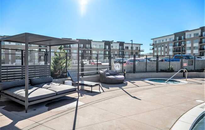 a rooftop patio with lounge chairs and a pool and a building in the background