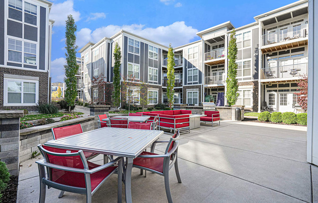 an outdoor patio with tables and chairs in front of an apartment building