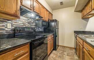 Renovated kitchen with updated appliances and dark wood cabinetry at Fountain Glen Apartments
