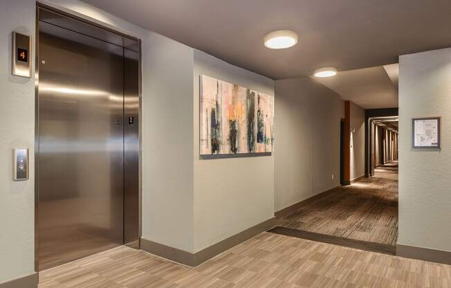 a hallway with a door to a elevator and a painting on the wall