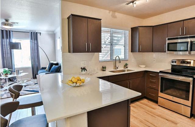 The Highland Apartments kitchen with brown cabinets, stainless appliances and quartz counters