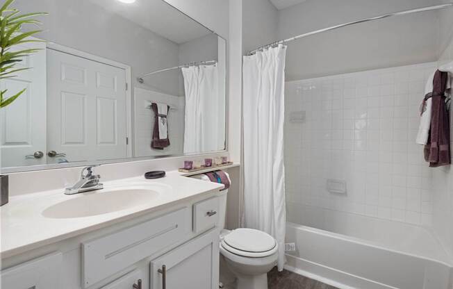 A white bathroom with a toilet, sink, and bathtub.