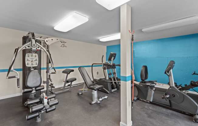 a gym with treadmills and other exercise equipment and a blue wall