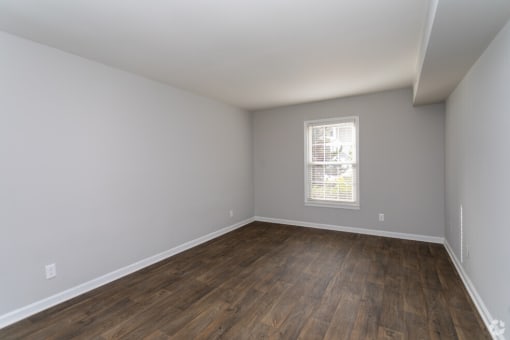 an empty living room with wood flooring and a window