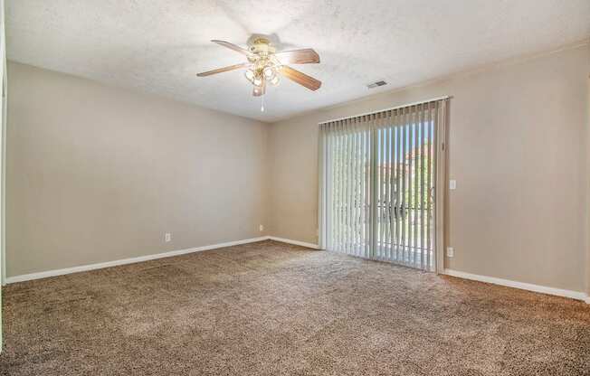 Omaha, NE Maple Ridge Apartments. A bedroom with a ceiling fan and a sliding glass door