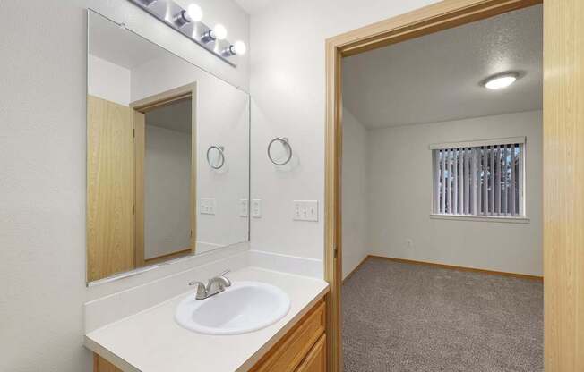 A bathroom with a sink, mirror, and lighting fixture.
