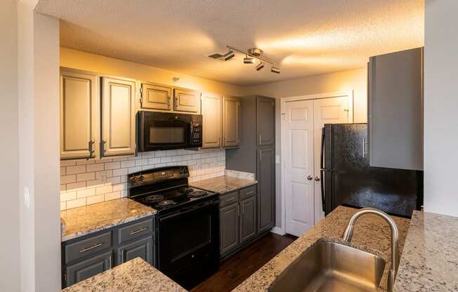 a kitchen with gray cabinets and black appliances