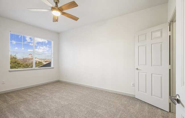 an empty living room with a ceiling fan and a window