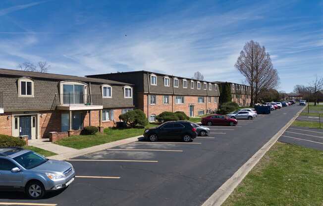 a row of apartment buildings with cars parked in a parking lot