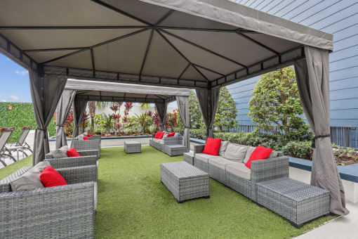 a lounge area with couches and chairs under a gazebo