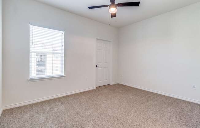 an empty living room with a ceiling fan and a window