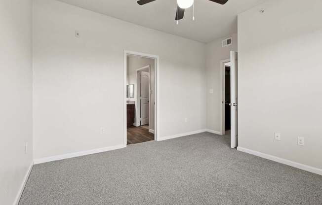 A room with a ceiling fan and carpeted floor.